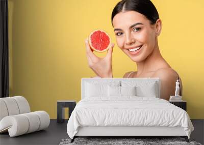 Beautiful woman with grapefruit and facial cream on color background Wall mural