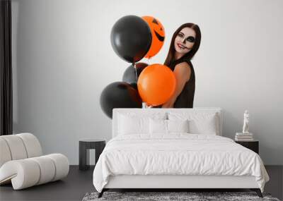 Beautiful woman with Halloween makeup and balloons on light background Wall mural