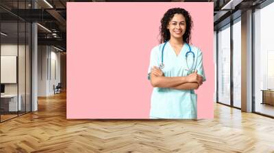 Beautiful young happy African-American female doctor with stethoscope on pink background Wall mural