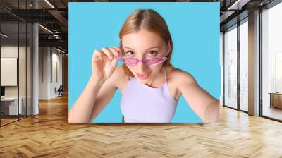 Beautiful young happy woman in stylish sunglasses taking selfie on blue background Wall mural