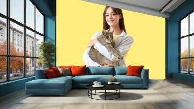 Beautiful young happy woman with cute cat on yellow background Wall mural