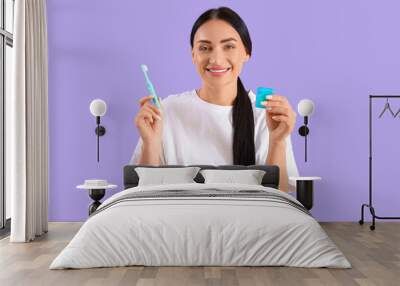 Beautiful young happy woman with dental floss and toothbrush on purple background Wall mural