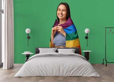 Beautiful young happy woman with piercing navel and LGBT flag on green background Wall mural