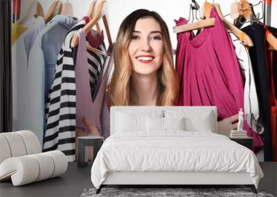 Beautiful young woman and rack with different clothes on white background Wall mural