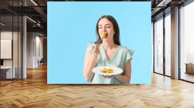 Beautiful young woman eating tasty ravioli on color background Wall mural