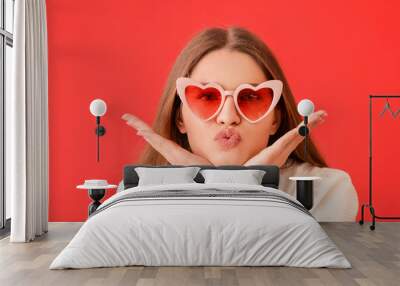 Beautiful young woman in stylish heart-shaped sunglasses on color background Wall mural