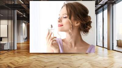 Beautiful young woman with bottle of perfume indoors Wall mural