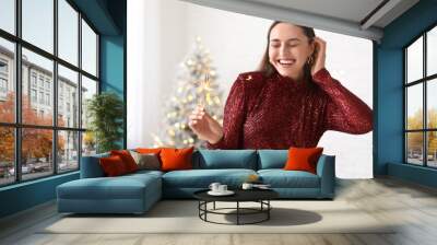 Beautiful young woman with Christmas sparklers in living room Wall mural