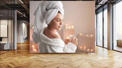 Beautiful young woman with cup of tea relaxing in spa salon Wall mural