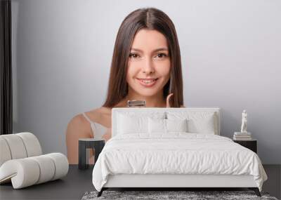 Beautiful young woman with eyelash curler and tweezers on light background Wall mural