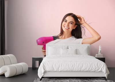 Beautiful young woman with hair dryer on color background Wall mural