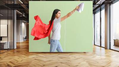 Beautiful young woman with iron on color background Wall mural