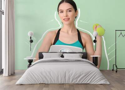 Beautiful young woman with measuring scales and dumbbell after weight loss on color background Wall mural