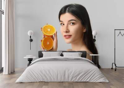 Beautiful young woman with orange  on grey background Wall mural