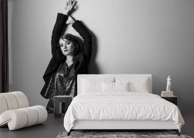 Black and white photo of beautiful fashionable woman near light wall Wall mural