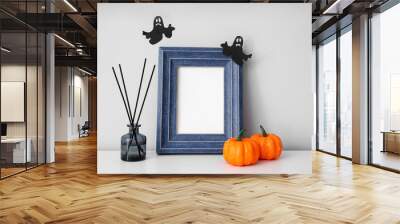 Blank photo frame with Halloween pumpkins and reed diffuser on mantelpiece near light wall Wall mural