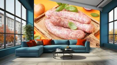 Board with raw fresh sausages and spices on orange background, closeup Wall mural