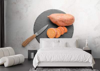 Board with raw sweet potato on light background Wall mural