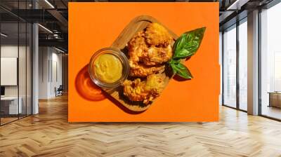 Board with tasty popcorn chicken and sauce on color background Wall mural