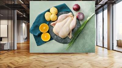 Board with whole raw chicken, orange and vegetables on color background Wall mural