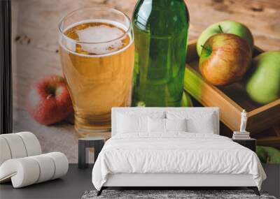 Bottle and glass of apple cider on table Wall mural