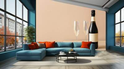 Bottle of champagne and glasses on wooden table near color wall Wall mural