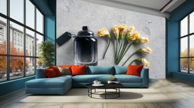 Bottle with perfume and withered flowers on grey background Wall mural