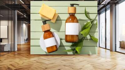 Bottles of shampoo and soap bars on green wooden background Wall mural