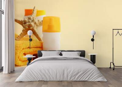 Bottles of sunscreen cream, starfish, towel and sunglasses on beige background Wall mural