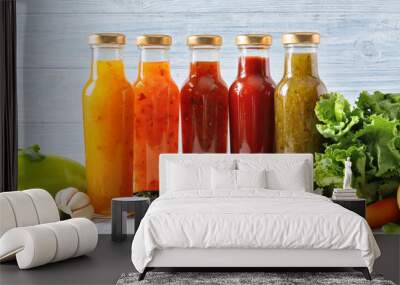 Bottles with different tasty sauces and vegetables on light table Wall mural