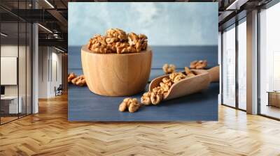 Bowl and scoop with tasty walnuts on color wooden table Wall mural