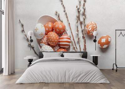 Bowl of painted Easter eggs and willow branches on light background Wall mural