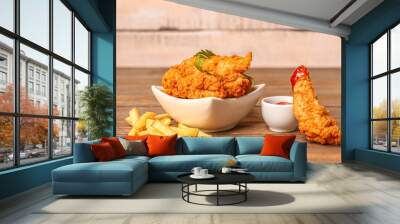 Bowl of tasty nuggets, sauce and french fries on wooden table Wall mural