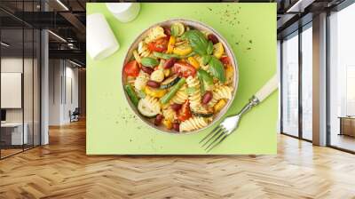 Bowl of tasty pasta salad with tomatoes and basil on green background Wall mural