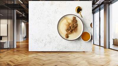 Bowl of tasty semolina porridge with nuts and cinnamon on light grunge background Wall mural