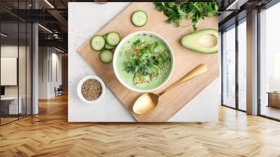 Bowl with green gazpacho and ingredients on light background Wall mural