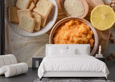 Bowl with tasty carrot hummus, lemon and crackers on light background, closeup Wall mural