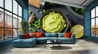 Bowl with tasty green pea hummus, lime and garlic on dark background, closeup Wall mural