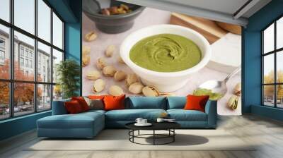 Bowl with tasty pistachio paste and spoon on pink grunge background Wall mural