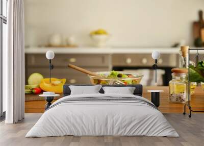 Bowl with tasty salad and ingredients on kitchen table Wall mural