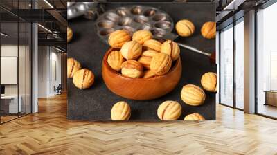 Bowl with tasty walnut shaped cookies and baking form on black grunge table, closeup Wall mural