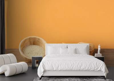 Bowls with tasty tahini, sesame seeds, bread and spinach on wooden table near color wall Wall mural