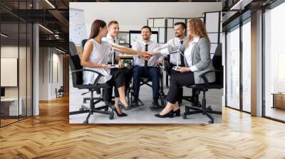 Business colleagues with wind turbine models putting hands together in office. Green energy concept Wall mural