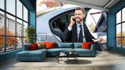 Businessman getting out of luxury car Wall mural