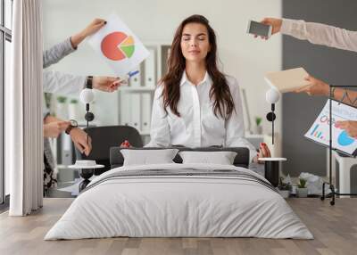 Businesswoman with a lot of work to do meditating in office Wall mural