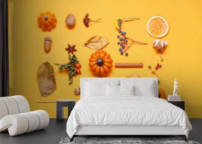 Candles in shape of pumpkin, autumn leaves and berries on yellow background Wall mural