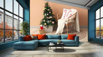 Christmas tree, wicker armchair with plaid and cup of cocoa drink near color wall Wall mural