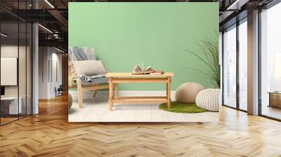 Coffee table with poufs, chair and houseplant near green wall Wall mural