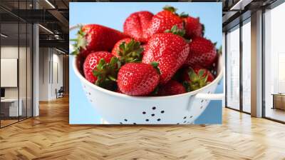 Colander with sweet fresh strawberries on blue background Wall mural