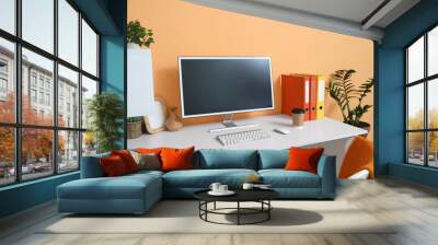 Comfortable workspace with modern computer near orange wall Wall mural